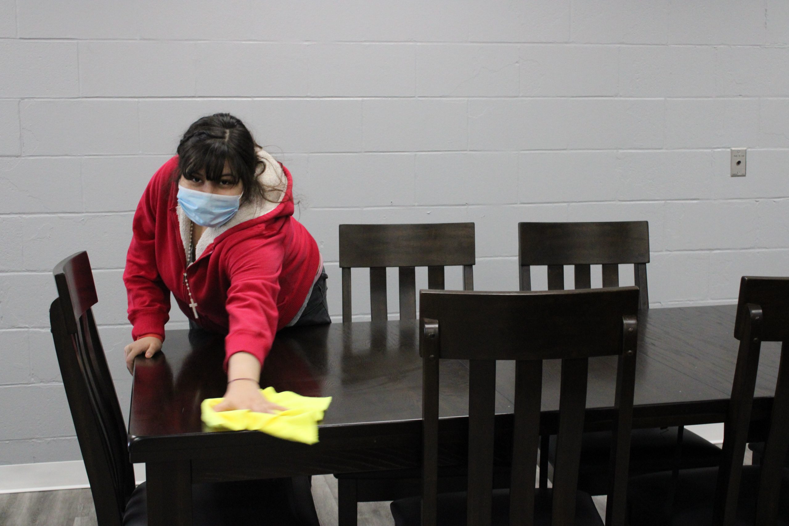 A student from the Care Academy Program cleaning tables.