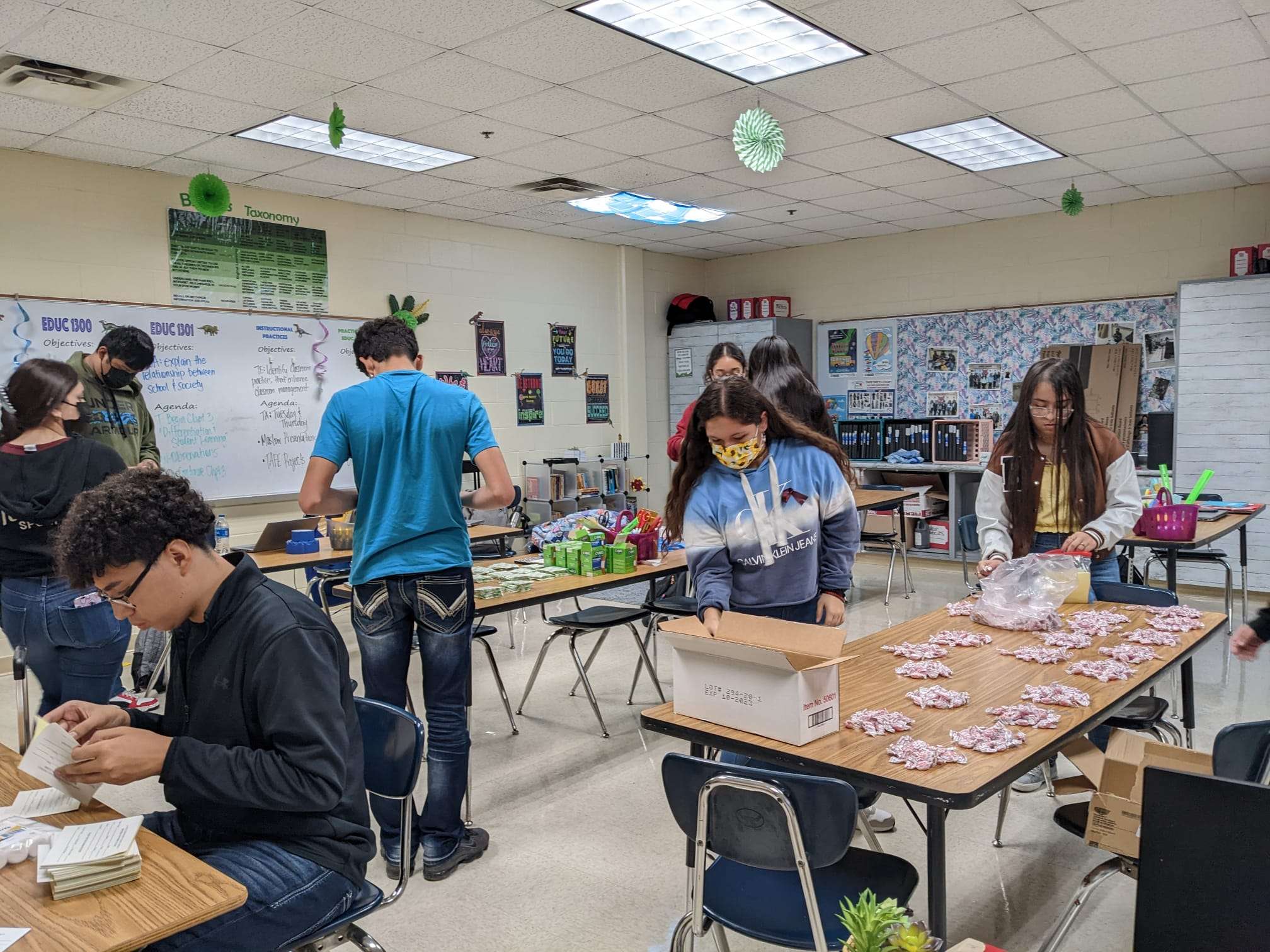 Students scattered around class gathering supplies into Ziplock bags for first aid kits.