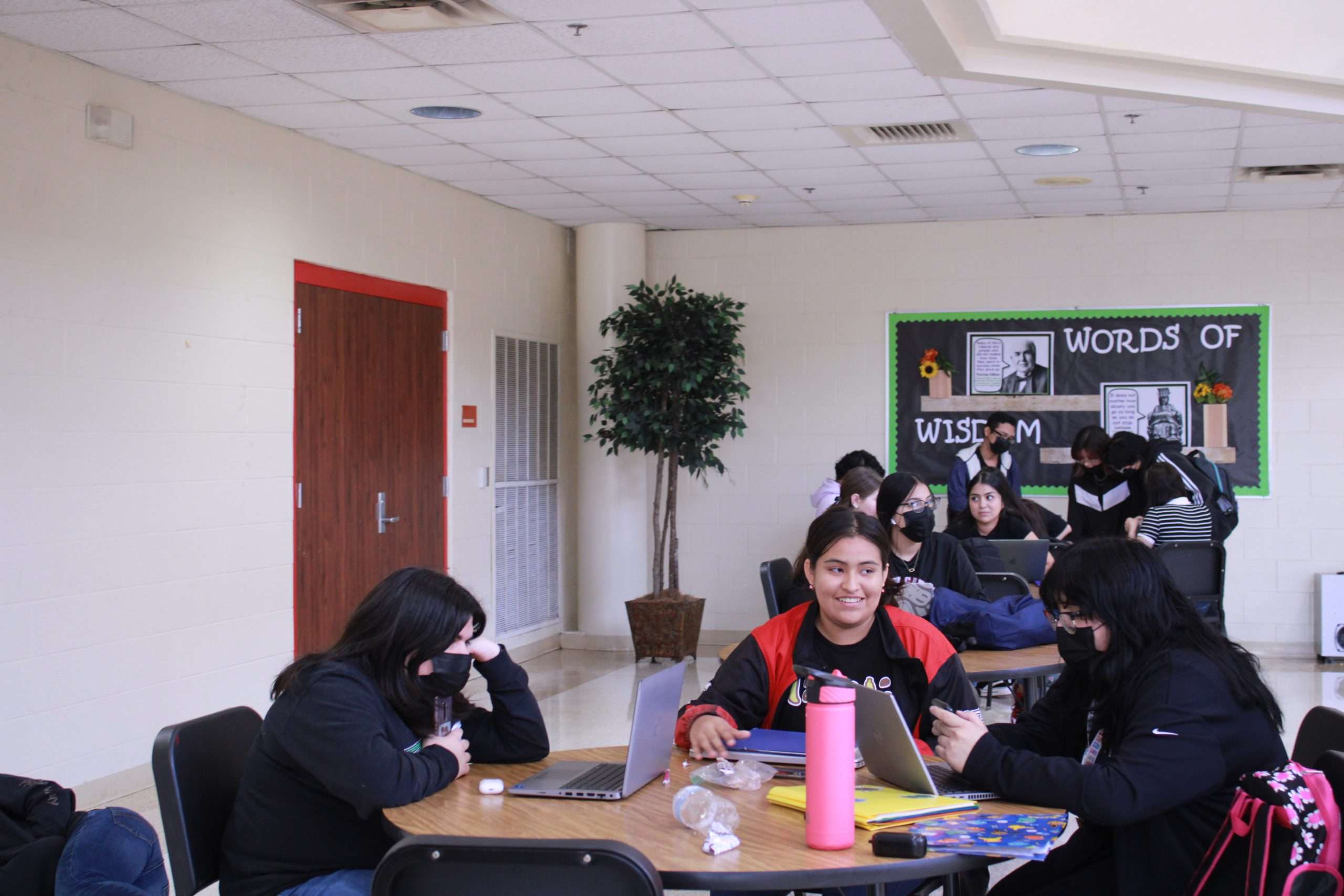 Students gather at tables with laptops out to do homework.