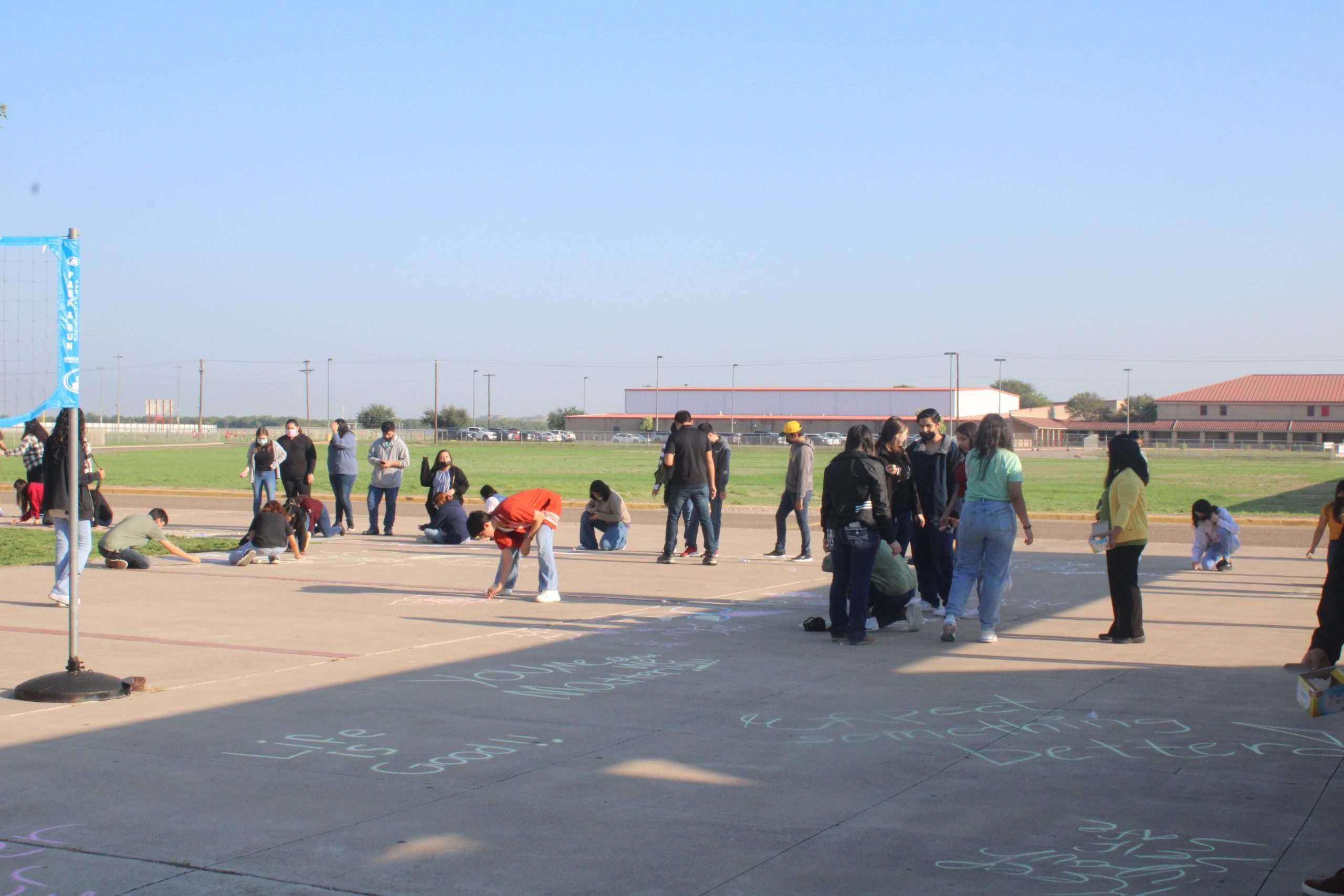 Students scatter by sidewalks and write on them with chalk