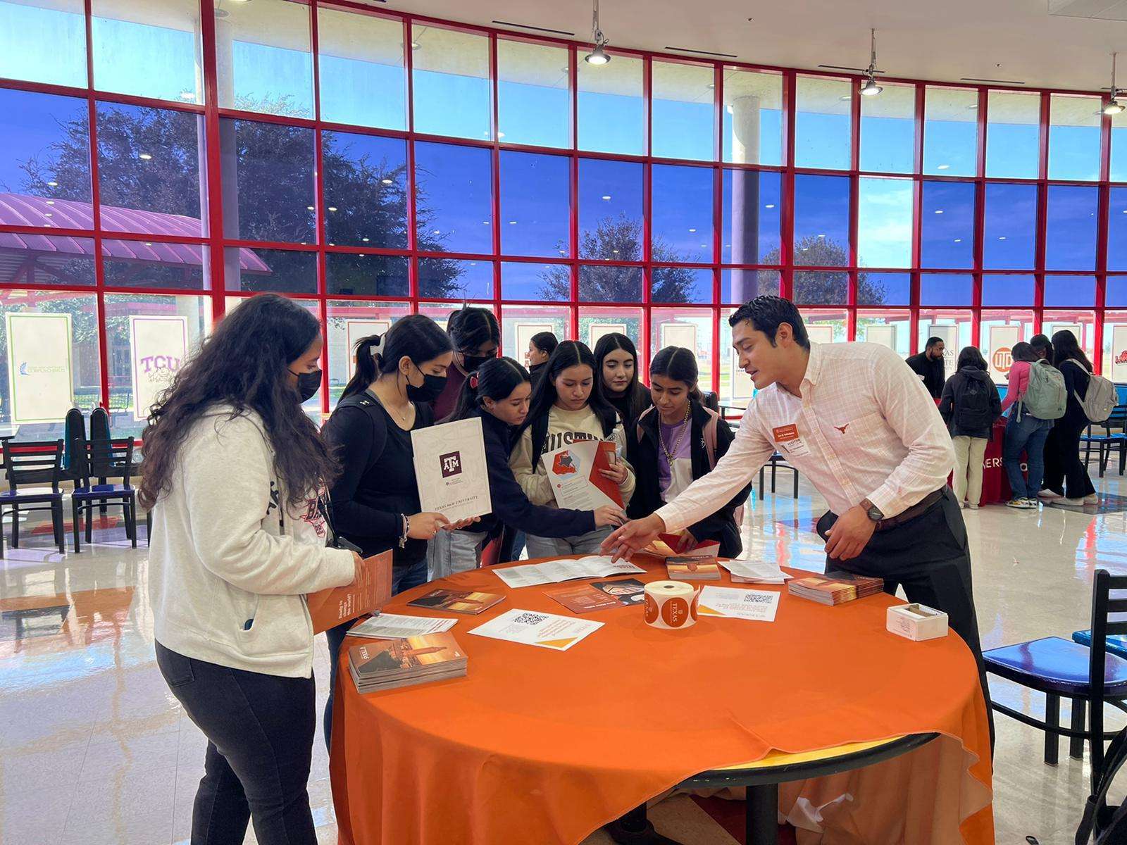Students gather at UT Austin's table during a college fair.